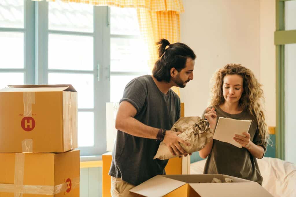 A couple is reviewing their moving checklist and is surrounded by boxes in the concept of moving to Romford.