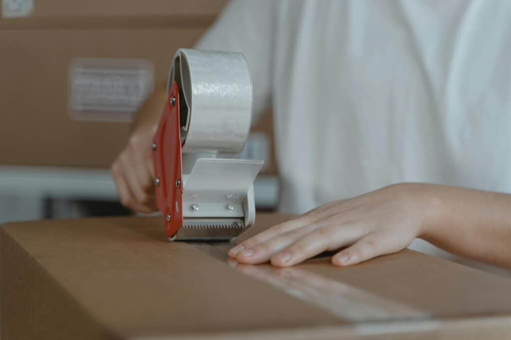 A closeup of packing tape sealing a cardboard in the concept of a Good man and van when moving to Romford.