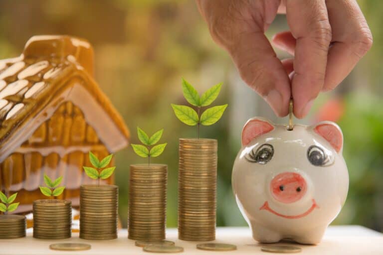 Stacks of coins, piggy bank, and a house figurine, in the concept of saving money when moving to Romford.