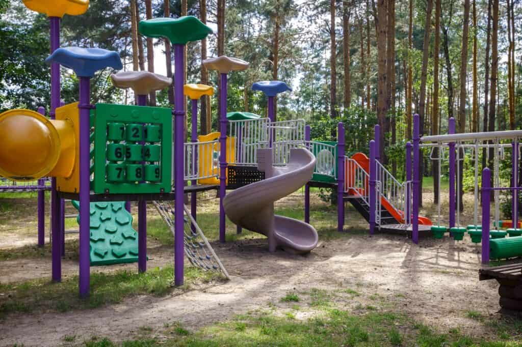 A colourful playground surrounded by trees in the concept of parks and green spaces in Romford.