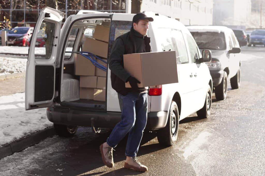 A man and van carrying a box one winter morning in the concept of 'Can You Use a Man and Van Service for Long Distance Moves'.